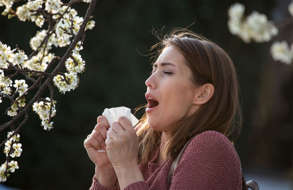 Person experiencing common allergy symptoms like sneezing, congestion, and itchy eyes.