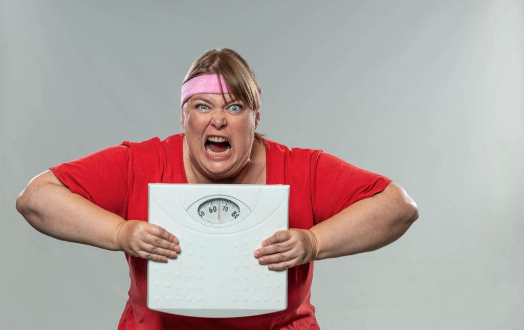 Image of a person looking slightly frustrated or overwhelmed while holding a scale